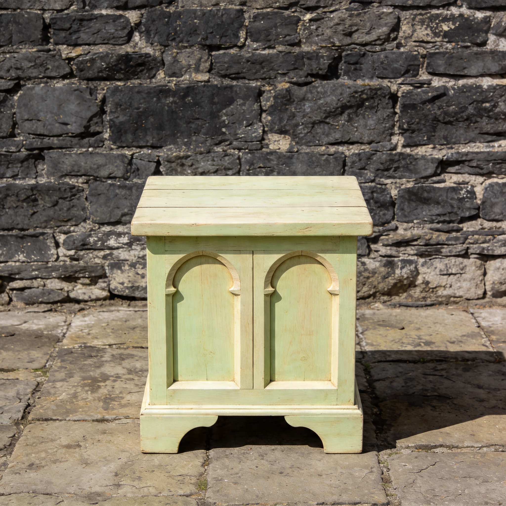 An arc-leg side table in haveli-teak reclaimed wood with forged black iron arc supports against a plaster wall.